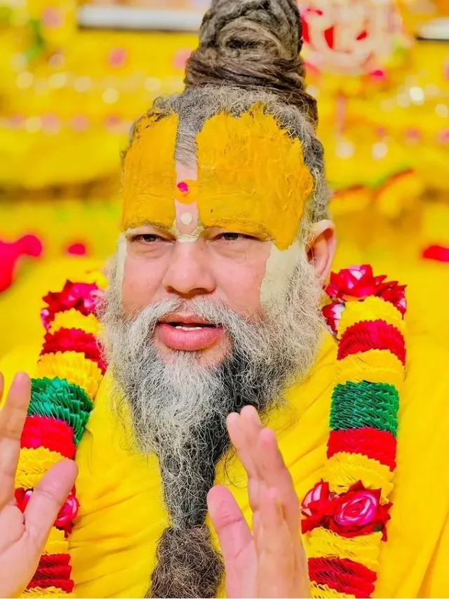 Premanand Ji Maharaj with hands folded, garlanded, at satsang in Vrindavan