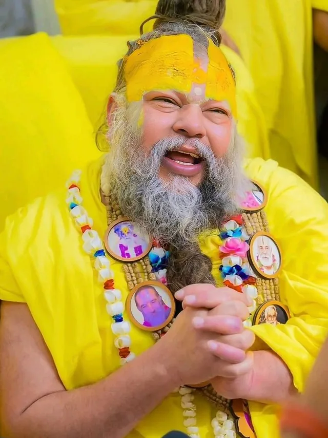 Premanand Ji Maharaj mid-satsang with a hand raised at Shri Hit Radha Keli Kunj, Vrindavan