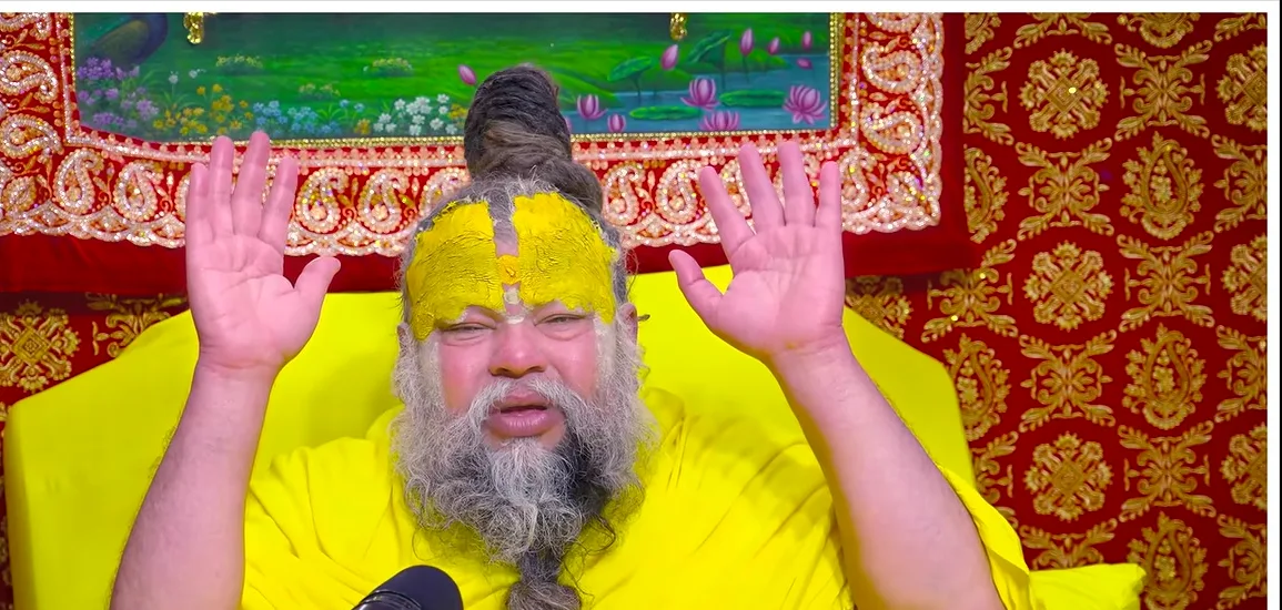 Premanand Ji Maharaj both hands raised in blessing before a red backdrop