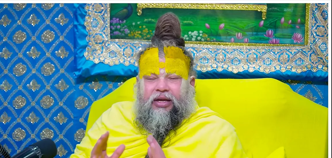 Premanand Ji Maharaj open hands before a blue backdrop