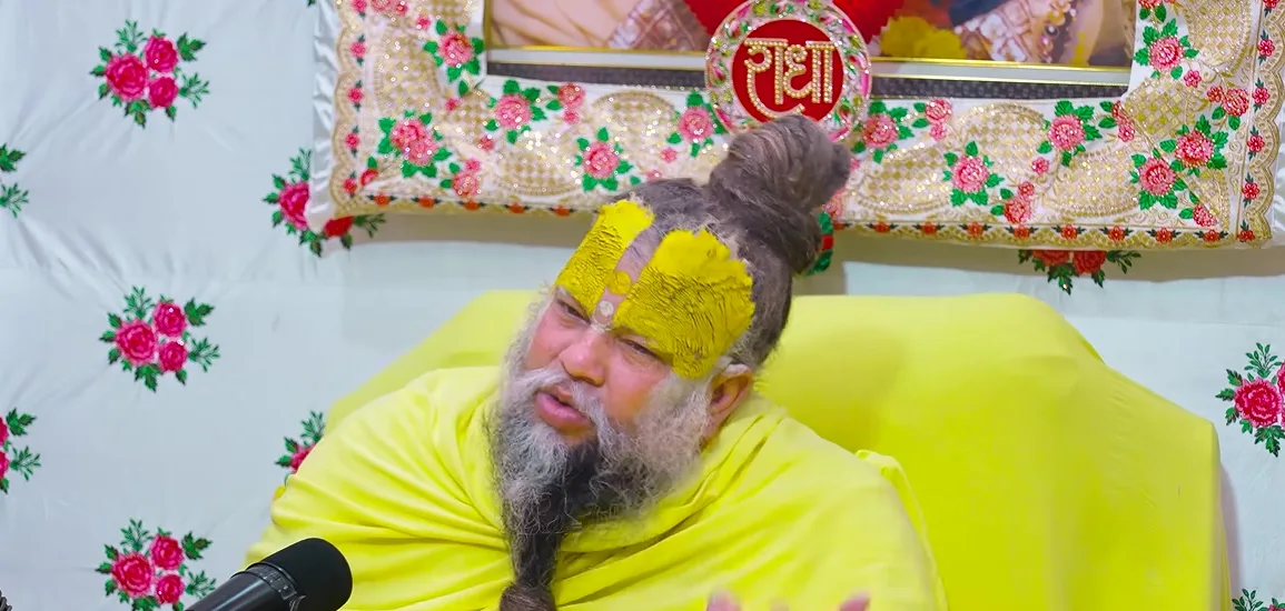 Premanand Ji Maharaj open hands, floral backdrop of the satsang hall