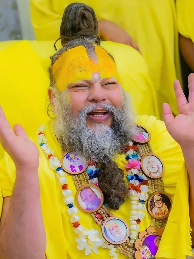 Premanand Ji Maharaj seated in the satsang hall with a microphone at Shri Hit Radha Keli Kunj, Vrindavan